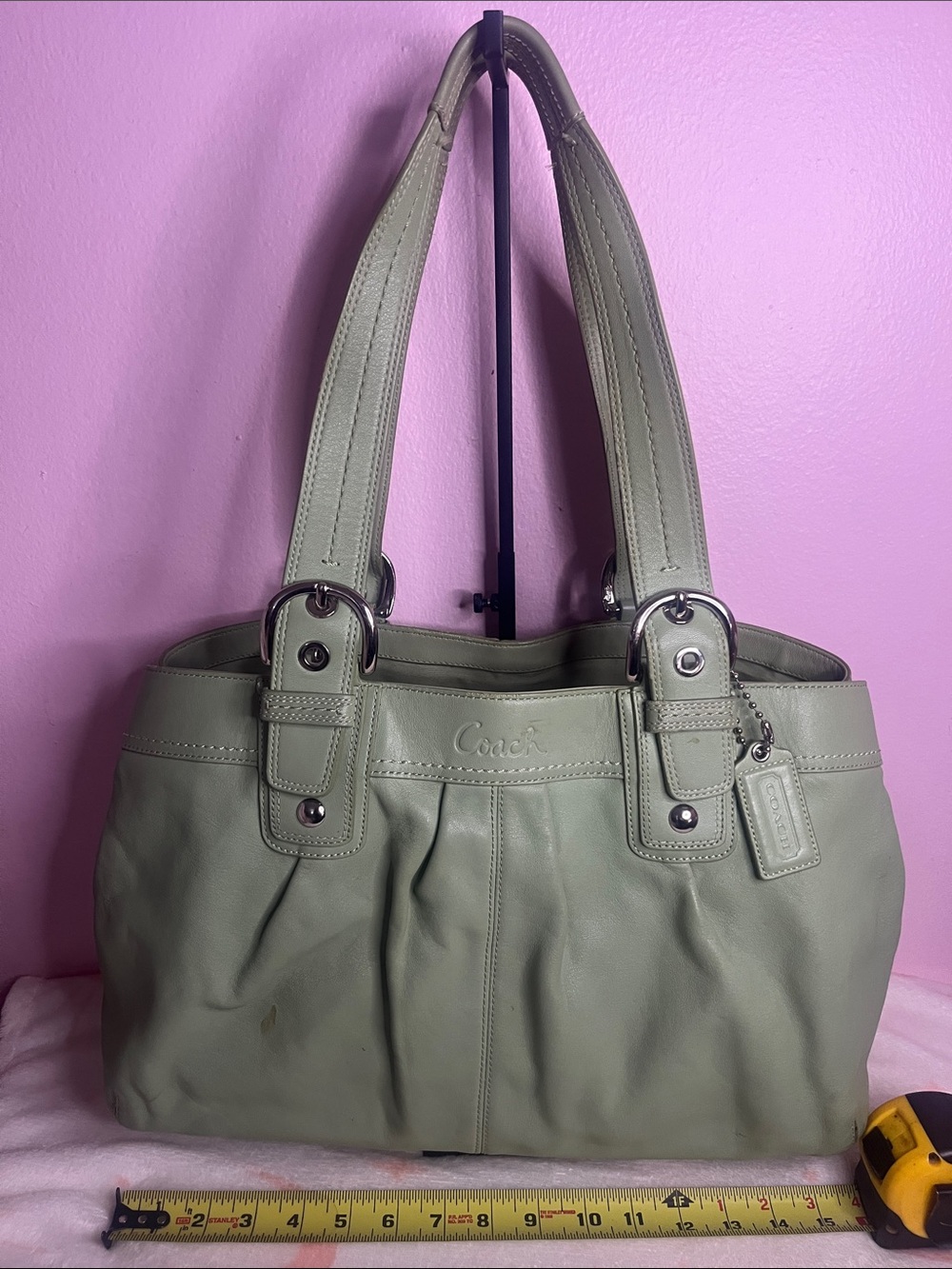 This Coach bag is a green canvas monogram hobo style with a leather creed patch